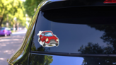 An Illustration Of A Sad Broken Down Red Cartoon Car Sticker on a Rear Car Window (New) example