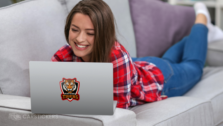 Student working on laptop with a die cut sticker on the front cover.