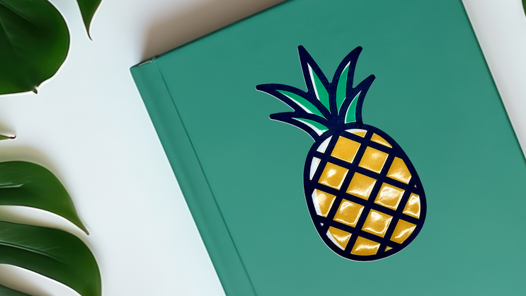 Embossed pineapple sticker applied to a notebook.