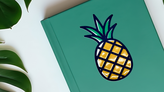 Embossed pineapple sticker applied to a notebook.