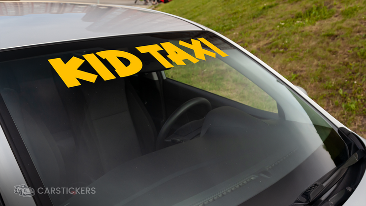 A funny windshield decal that reads Kids Taxi applied to vehicle.