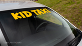 A funny windshield decal that reads Kids Taxi applied to vehicle.