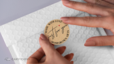 A thank you kraft paper sticker being applied to an envelope