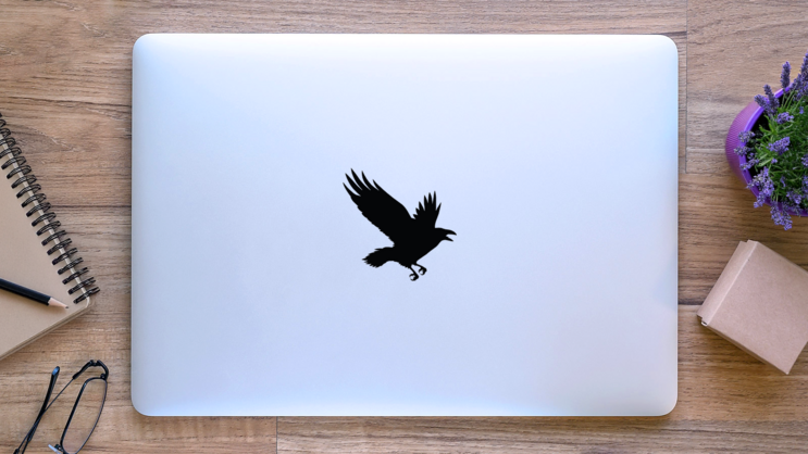 The Black Silhouette Of A Crow Flying Rook Sticker on a Laptop (New) example