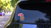 The Cat In Sunglasses Holds A Pink Donut Sticker on a Rear Car Window (New) example